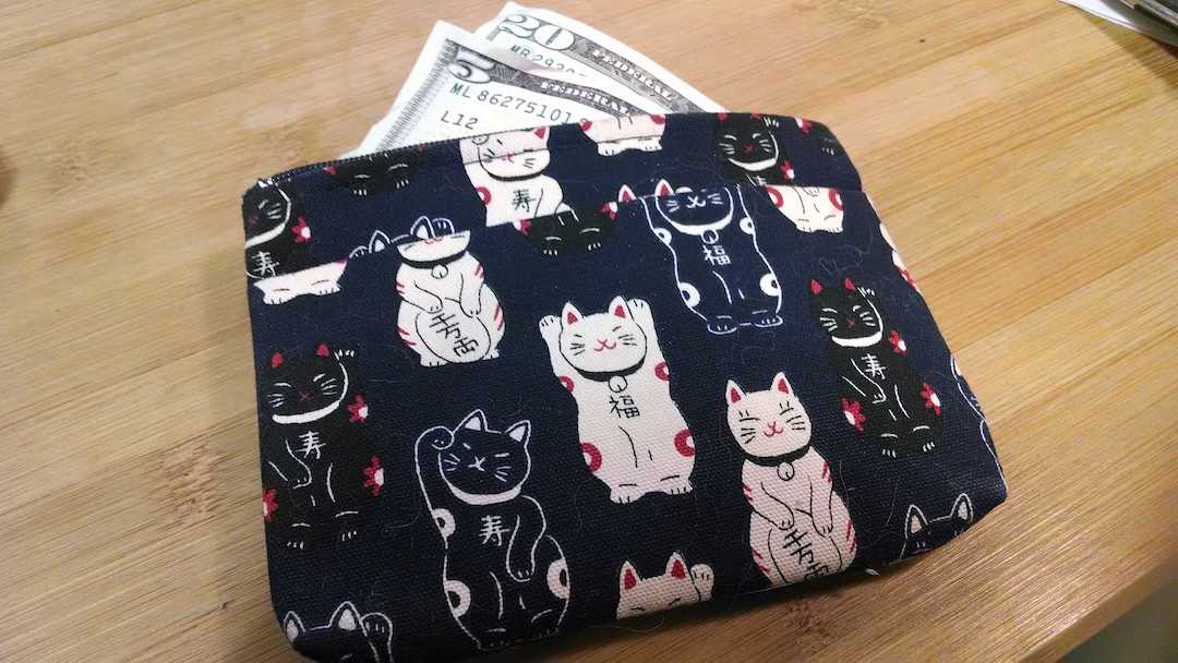 What is a money market account? How does a money market account work? | Photo of a wallet with a Japanese pattern of good luck cats; money sticking out of a wallet | Photo by Evan Sachs