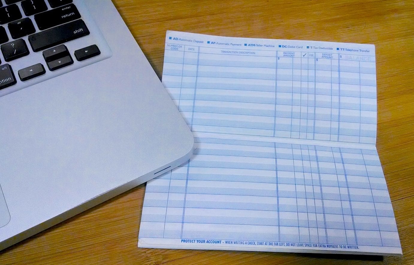Demystifying the 50/30/20 Rule for Budgeting | Photo of bankbook and computer on a wood desk | Photo by Evan Sachs