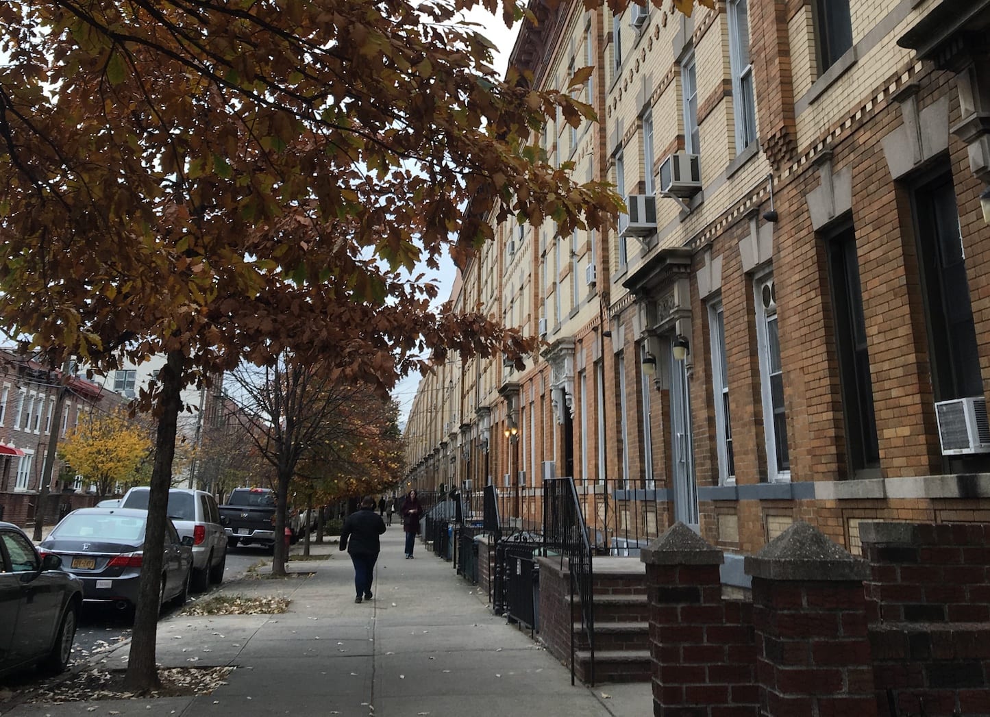 Effects of Poverty: Can You Be Too Poor for Financial Literacy? | Photo of somebody walking down the sidewalk past rows of apartments | Photo by Emma Finnerty